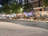 outdoor seating and tables along a walkway at night on a city street in the fall