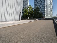 skateboarder in the middle of an urban park near tall buildings with green trees on one side and gray building