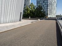 skateboarder in the middle of an urban park near tall buildings with green trees on one side and gray building