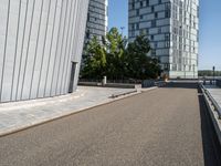 skateboarder in the middle of an urban park near tall buildings with green trees on one side and gray building