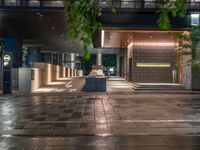 a large brick sidewalk with a store front at night time and a sign that says