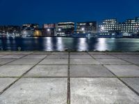 a city by the water is lit up at night time with no clouds in the sky