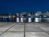 a city by the water is lit up at night time with no clouds in the sky