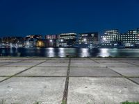 a city by the water is lit up at night time with no clouds in the sky