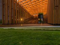 a wooden walkway that leads to a pavilion surrounded by lawn space and stairs in the evening