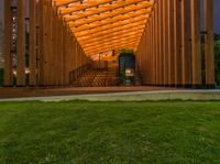 a wooden walkway that leads to a pavilion surrounded by lawn space and stairs in the evening