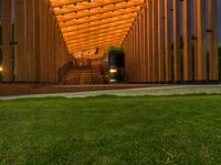 a wooden walkway that leads to a pavilion surrounded by lawn space and stairs in the evening