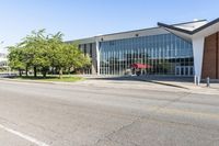 the exterior of a modern building with an red umbrella near by in front of a grassy lawn