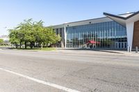 the exterior of a modern building with an red umbrella near by in front of a grassy lawn