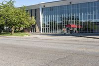 the exterior of a modern building with an red umbrella near by in front of a grassy lawn