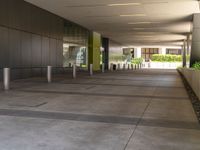 a metal barrier sits near the outside entrance to the building as people walk by the windows