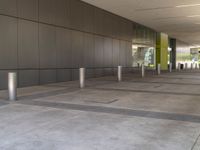 a metal barrier sits near the outside entrance to the building as people walk by the windows