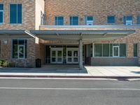 the city library building has white awnings on the front of it and is open to the street