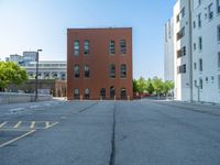 a street with a building near the building in the middle and on the left of which is a parking lot, as shown in this photo