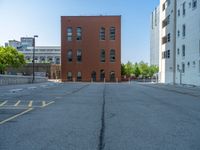 a street with a building near the building in the middle and on the left of which is a parking lot, as shown in this photo