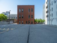 a street with a building near the building in the middle and on the left of which is a parking lot, as shown in this photo