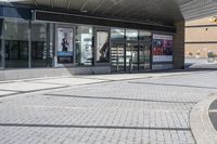 a person sitting at the bench in front of a mall that is empty of people