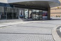 a person sitting at the bench in front of a mall that is empty of people