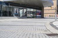 a person sitting at the bench in front of a mall that is empty of people