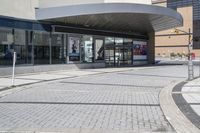 a person sitting at the bench in front of a mall that is empty of people