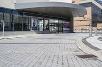 a person sitting at the bench in front of a mall that is empty of people