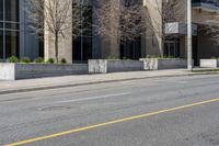 the building is painted stone with yellow lines on the curb of the street and next to the street is a sidewalk