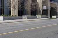 the building is painted stone with yellow lines on the curb of the street and next to the street is a sidewalk