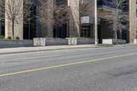 the building is painted stone with yellow lines on the curb of the street and next to the street is a sidewalk