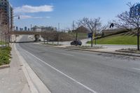 a street near a highway with buildings in the background on a sunny day from the sidewalk