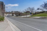 a street near a highway with buildings in the background on a sunny day from the sidewalk