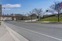 a street near a highway with buildings in the background on a sunny day from the sidewalk