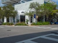 a man crossing the street with his skateboard, in front of the dojo building