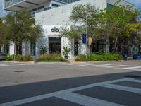 a man crossing the street with his skateboard, in front of the dojo building