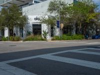 a man crossing the street with his skateboard, in front of the dojo building