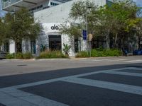 a man crossing the street with his skateboard, in front of the dojo building