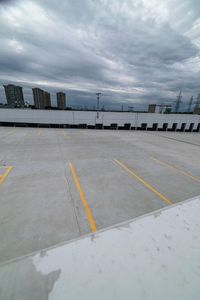 a parking lot with two yellow lines painted on the concrete area with tall buildings in the distance