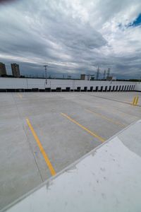 a parking lot with two yellow lines painted on the concrete area with tall buildings in the distance