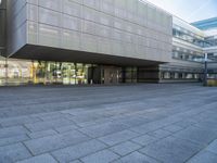 a very large building that is on a road side walk area with glass windows and concrete steps