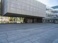 a very large building that is on a road side walk area with glass windows and concrete steps