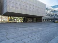 a very large building that is on a road side walk area with glass windows and concrete steps