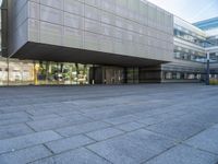 a very large building that is on a road side walk area with glass windows and concrete steps