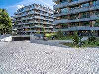 the modern apartment block is next to an empty sidewalk and sidewalk with a stone bench near by it