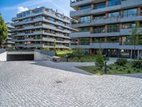 the modern apartment block is next to an empty sidewalk and sidewalk with a stone bench near by it