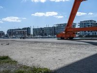 a crane moving in to shore of a marina next to a body of water with buildings