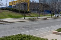 street view of a city and business complex on the corner of a hill with bushes in front