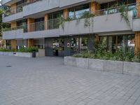 two people skateboarding in a courtyard in front of a multi - unit apartment building