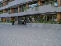 two people skateboarding in a courtyard in front of a multi - unit apartment building