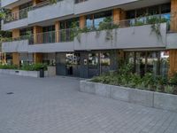 two people skateboarding in a courtyard in front of a multi - unit apartment building