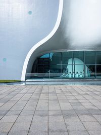 a building with a large curved white facade on it's face near the glass windows