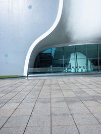 a building with a large curved white facade on it's face near the glass windows